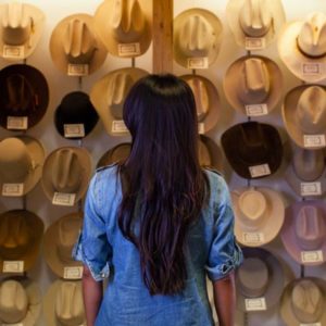 woman looking at vintage cowboy hats